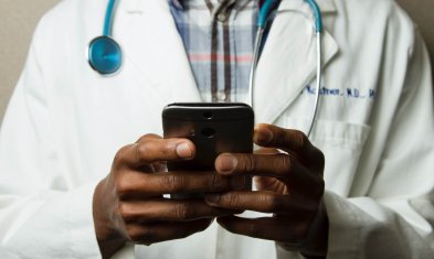 Recruiting in Krankenhäusern Titelbild: Bild zeigt Nahaufnahme einer medizinischen Arbeitskraft, die ihr Smartphone in den Händen hält